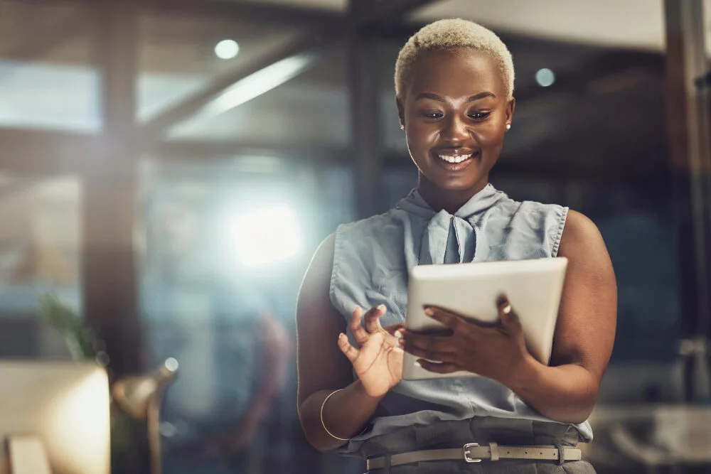 Femme souriante consultant une tablette dans un bureau lumineux