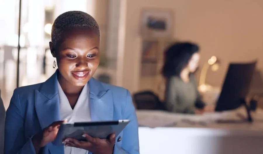 Femme d’affaires souriante sur sa tablette dans un bureau
