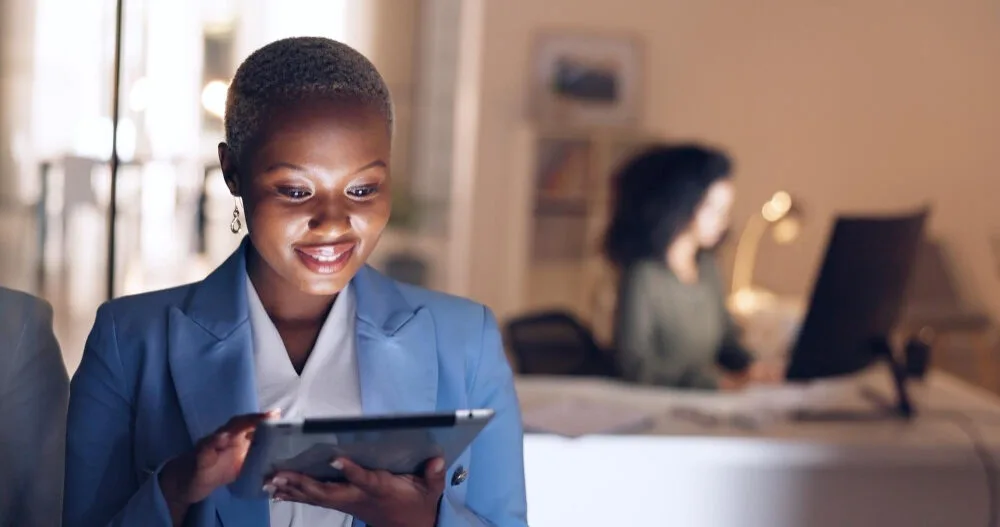Femme d’affaires souriante sur sa tablette dans un bureau