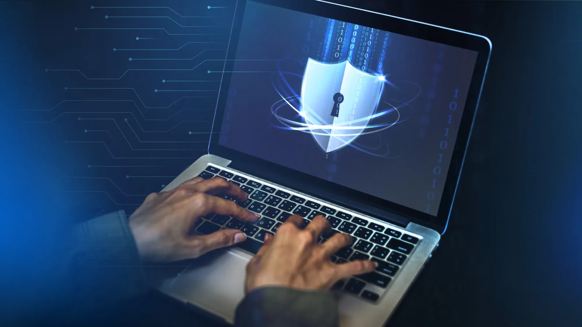 Des mains sur le clavier d’un ordinateur portable dont l’écran affiche un bouclier de protection